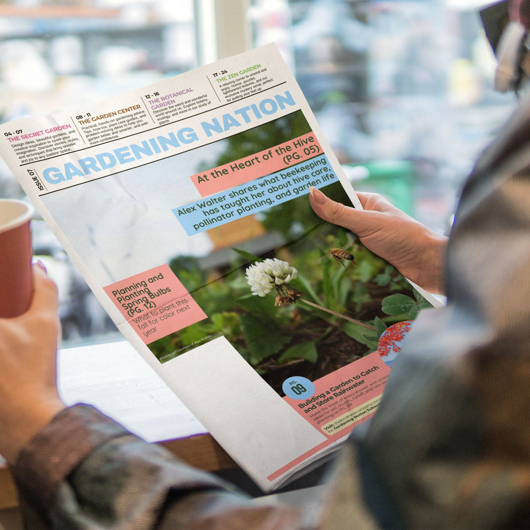 A person holding a copy of Gardening Nation magazine next to a paper cup in a bright, real-world setting.